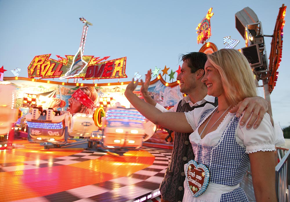 Veranstaltungen Bayerischer Wald: Gäste in bayerischen Trachten vor einem Fahrgeschäft auf dem Straubinger Gäubodenvolksfest