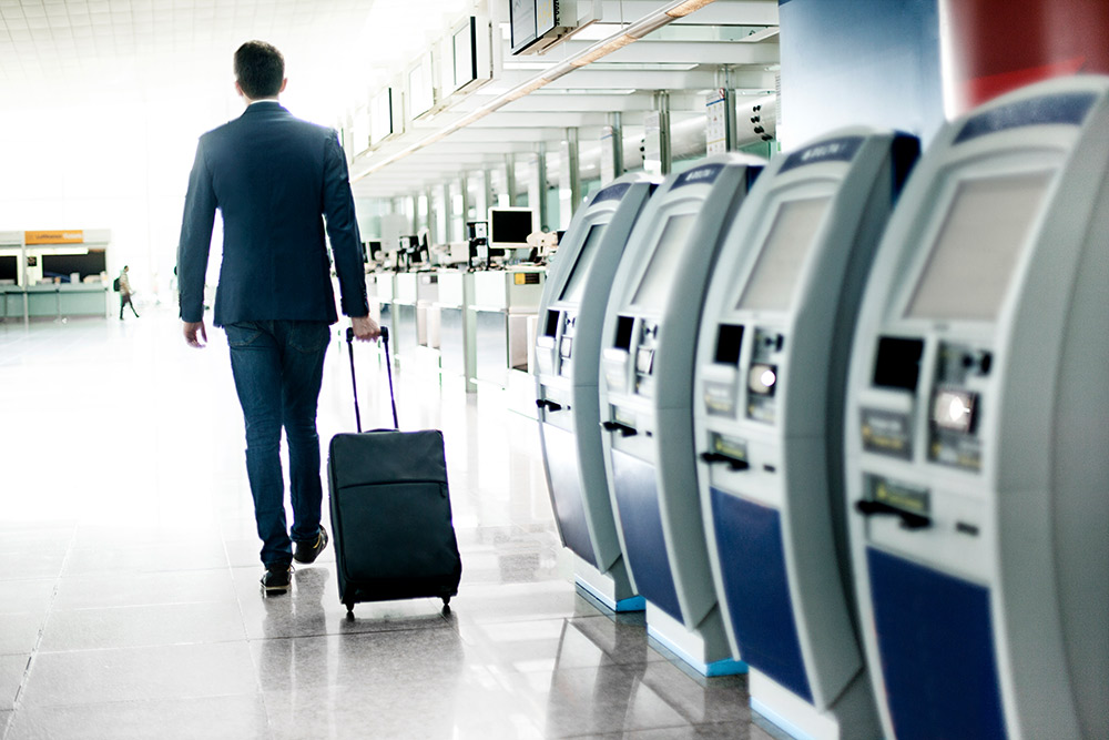 Geschäftsmann mit Rollkoffer am Flughafen