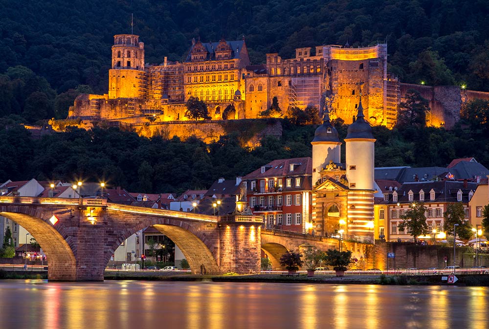 Block auf das Heidelberger Schloss in Abendbeleuchtung mit Alter Brücke im Vordergrund